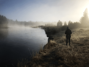 A angler stands on the bank of the Madison River